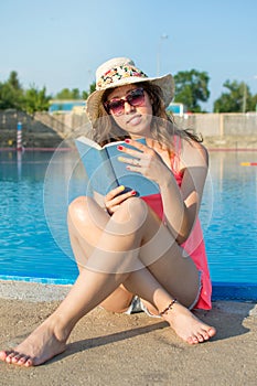 Girl reading a book by the pool.