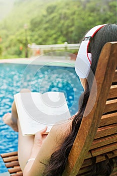 Girl reading a book by the pool