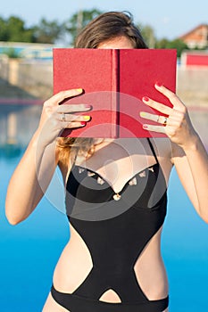 Girl reading a book by the pool. Summer vacation
