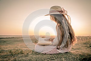 Girl reading the book on rural landscape