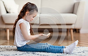 Girl Reading Book Sitting On Floor At Home On Weekend