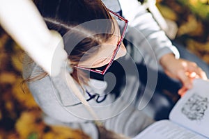 Girl reading a book while sitting on a garden swing - shot from