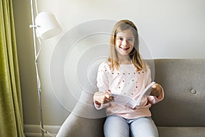 Girl Reading Book On Sofa In Living Room At Home