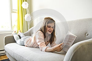 Girl Reading Book On Sofa In Living Room At Home