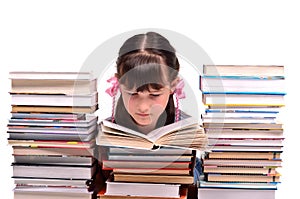 Girl reading a book among stacks of books