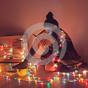 Girl reading a book under blanket at home