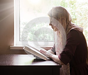 Girl reading a book by the window