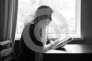 Girl reading a book by the window