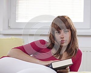 Girl holding a closed book looking at you photo