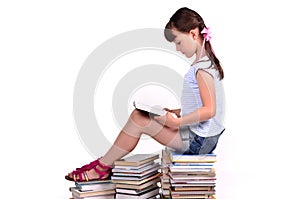 Girl reading a booksitting on big pile of books