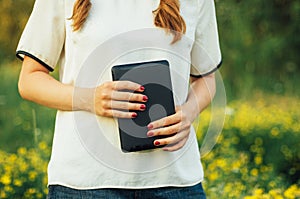 Girl reading on digital tablet on the grass. Young woman using her digital tablet outdoors. Young working on her tablet outdoors