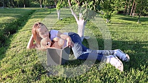 Girl reading outdoors to her little teddy bear. little girl with toys plays on the lawn