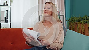 Girl reading paper documents, reviewing reports, calculate costs, incomes, expenses, working at home