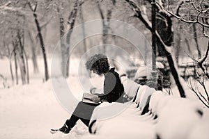 Girl reading in the snow, sitting on a bench