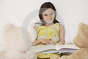 Girl Reading Story Book To Her Teddy Bears