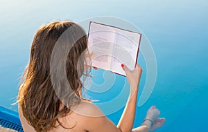 Girl reading by the swimming pool