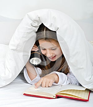 Girl reading under blanket