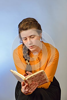 A girl reads the Bible while sitting on a chair on a blue background. The inscription in Russian -