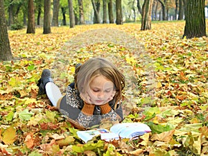 Girl reads a book in the autumn park