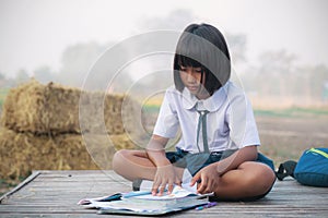The girl reads a book on bamboo mat