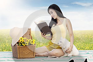 Girl reads book with dog at field