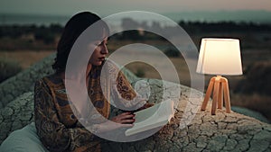 Girl reads book on the mountain with abat jour at night