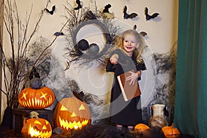 girl reads book spells. Halloween blonde witch. Magic wand in hands of magician.