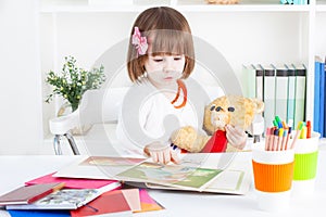 Girl reads a picture book to a teddy bear