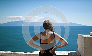 Girl from rear enjoying view of the sea