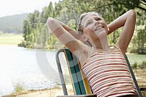 Girl Reclining On Deckchair By Lake