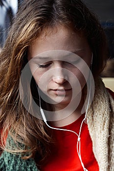 Girl with red-brown hair listening to music with his eyes closed