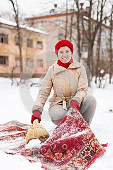 Girl in red cap cleans carpet with snow