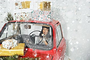 Girl in red car with Christmas gifts