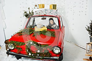 Girl in red car with Christmas gifts