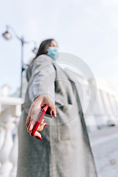 Girl with a red cell phone in hand in a cityscape. Phone close up