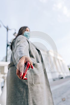 Girl with a red cell phone in hand in a cityscape. Phone close up