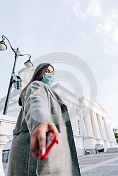 Girl with a red cell phone in hand in a cityscape. Phone close up