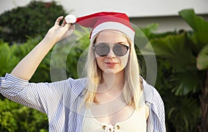 Girl in a red Christmas hat next to the swimming pool with blue water. Holiday concept.