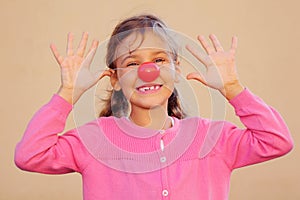 Girl with red clown nose smiles