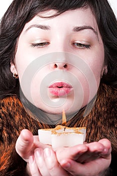 Girl in red coat blow on candle