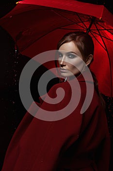 The girl in a red coat with a red umbrella in the rain