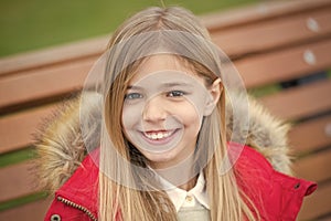 Girl in red coat sit on bench in park