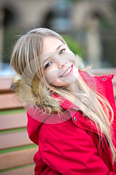 Girl in red coat sit on bench in park