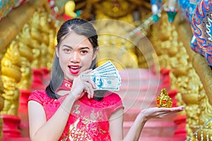 The girl in the red dress of Chinese descent is happy with red envelope with the dollar