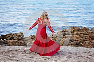 Girl in Red Dress Dances on the Sand at the Beach