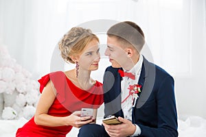 A girl in a red dress with a guy holding a mobile phone.