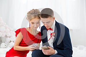 A girl in a red dress with a guy holding a mobile phone.