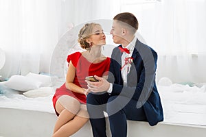 A girl in a red dress with a guy holding a mobile phone.