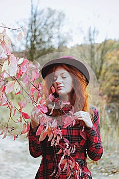 Girl in red dress and hat walking in autumn forest