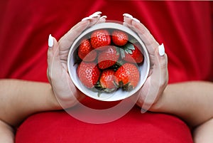 Girl in red dress holding plate of strawberries. White plate with strawberry. Healthy lifestyle. Fruit vitamin.